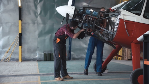 Two Mechanics Working on a Small Aircraft
