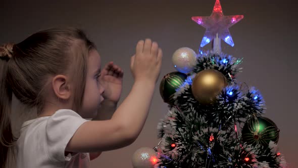 Beautiful Little Girl Decorates Christmas Tree with Colorful Balls