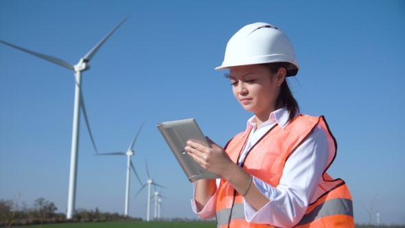 Woman with Hard Hat Against Wind Turbine