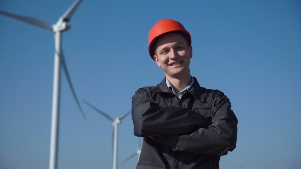 Smiling Engineer Standing Against Wind Farm