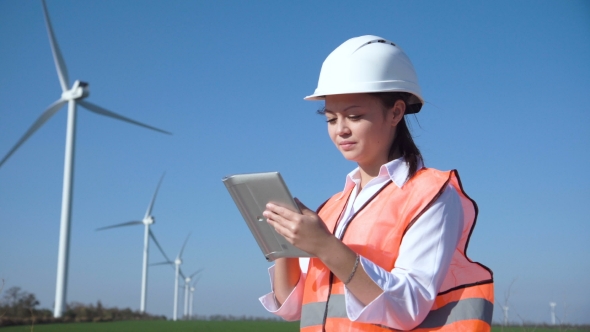 Woman with Hard Hat Against Wind Turbine