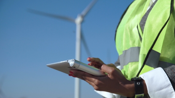 Engineer Using Digital Tablet Against Wind Turbine