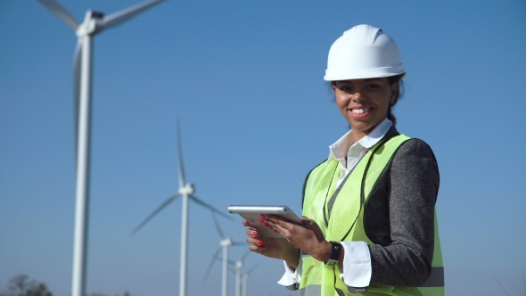 Woman with Hard Hat Against Wind Turbine