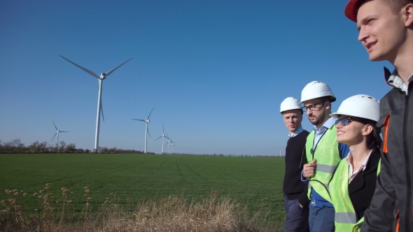 Group of Engineers Walking Against Wind Farm