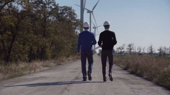 Two Engineers Walking Towards Wind Farm