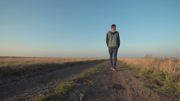 Young Man Walking Away Down a Rural Road