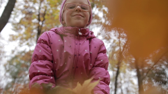 Smiling Girl Throwing Maple Leaves in Autumn