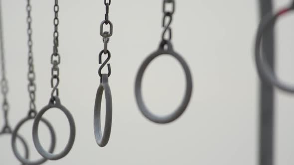 Individuals swinging on traveling rings on Santa Monica beach.