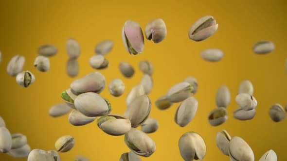 Closeup of Salted Pistachios Flying Up on a Yellow Background