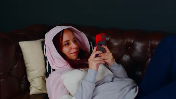 Young Woman Browsing Mobile Phone and Lying on Sofa