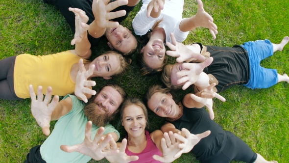 Happy Friends Lying on Grass and Waving Hands