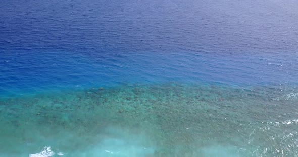 Tropical drone travel shot of a white paradise beach and aqua blue ocean background in vibrant 4K