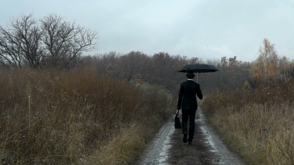 Man with Umbrella Walks in Autumn Forest