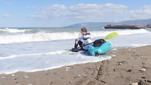 A Young Man with a Kayak on the Seashore