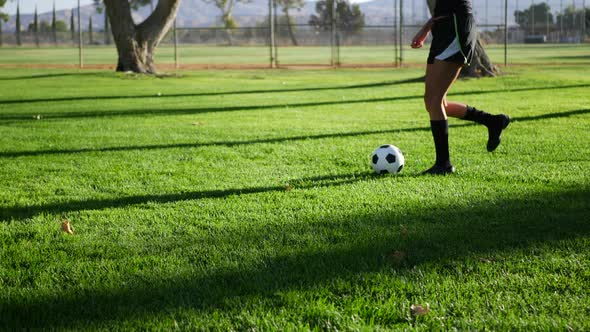 A female womens soccer player running and dribbling a football up the field during a team sports pra