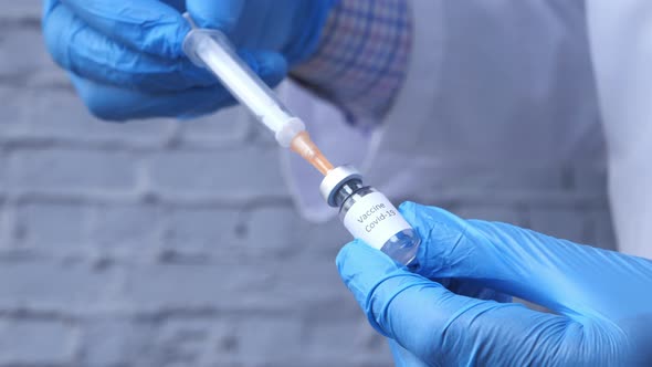 Doctor Hands in Medical Gloves Holds Syringe and Vaccine.