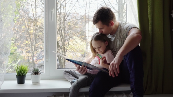 Little Girl Reading a Book with His Father