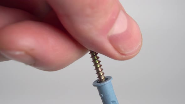 Unscrewing the dowel nail by hand on a white background. Galvanized thread with plastic fastening