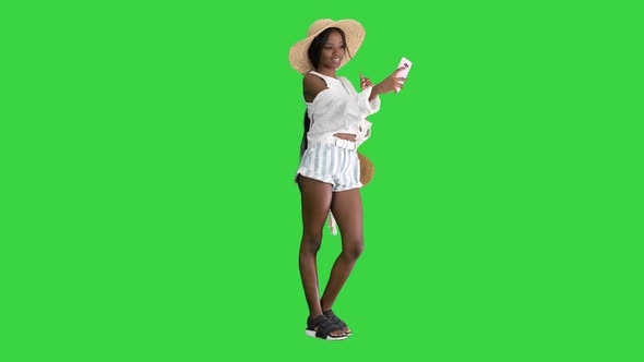 Smiling African American Woman Wearing Straw Hat and Taking Selfie on Smartphone on a Green Screen