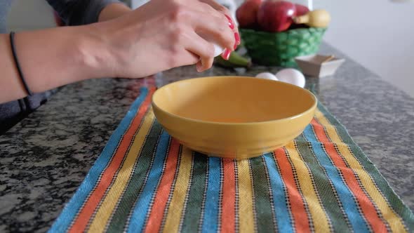 Woman hands breaking the shell of an egg and pouring it into a bowl