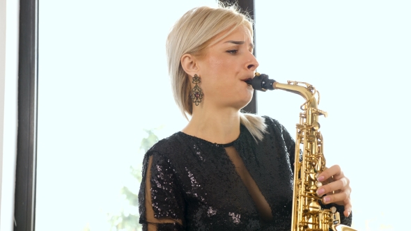 Beautiful Saxophonist Woman Playing at the Sax in the Living Room