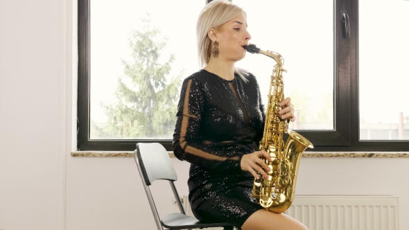 Beautiful Saxophonist Woman Playing at the Sax in the Living Room
