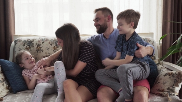 Happy Family with Children Hugging on Sofa at Home