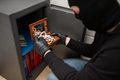 thief stealing valuables from safe at crime scene - PhotoDune Item for Sale