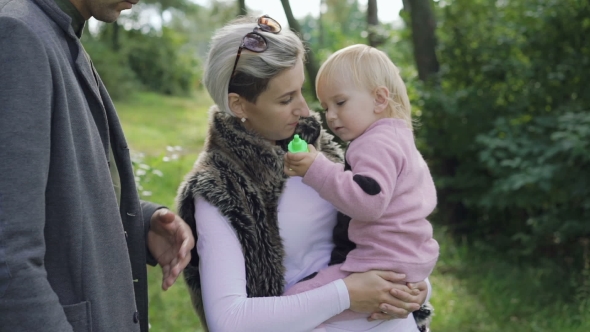 Happy Family Rest on the Nature with Kid, Blowing and Catching Bubbles