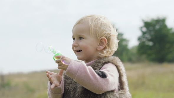 Portrait of Happy, Smiling Little Kid Blows the Bubbles on Nature