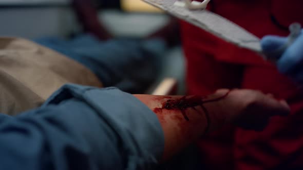 Unrecognizable Paramedic in Gloves Wrapping Man Hand with Elastic Bandage