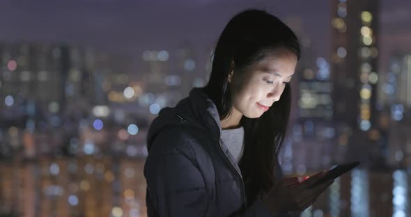 Woman using mobile phone over city background at night