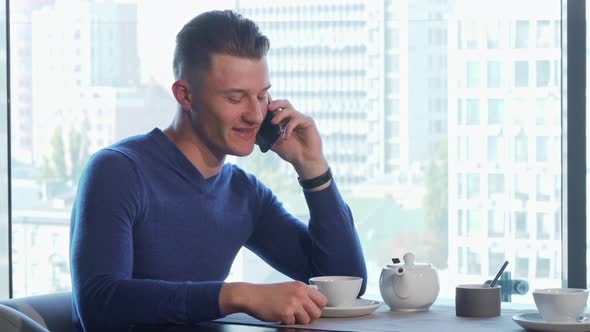 Handsome Man Enjoying Drinking Tea and Talking on the Phone at the Restaurant