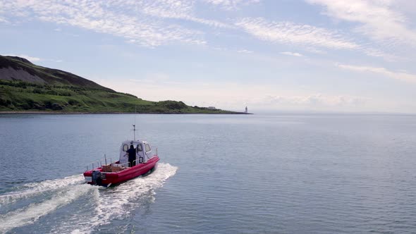 A Small Cargo Ferry at Sea Motoring Alongside an Island