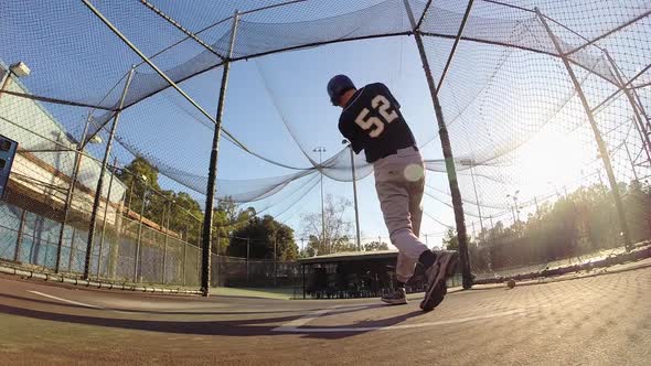 A baseball player practicing at the batting cages.