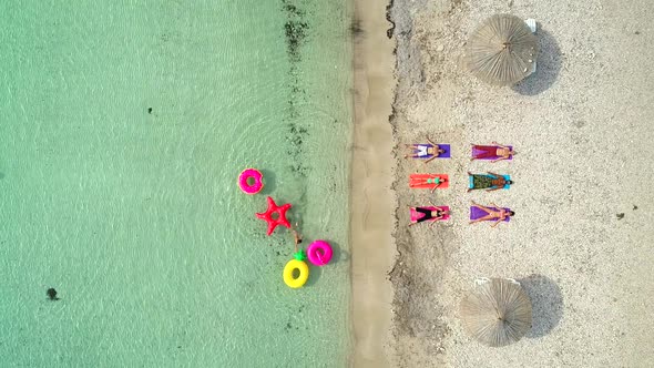 Aerial view of people lying in yoga pose on on the with inflatables.