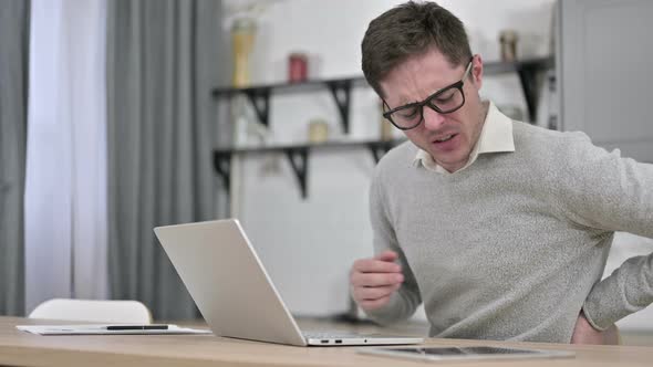 Young Man with Spinal Back Pain Working on Laptop