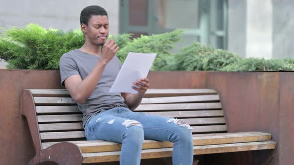 Young African Man Reading Documents in Disappointment Outdoor 