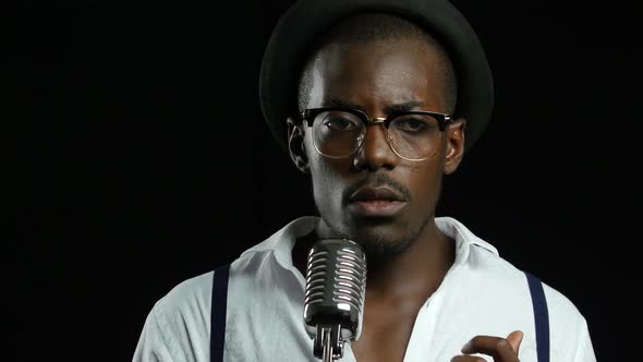 Guy with a Mustache and Beard Sings Into a Retro Microphone. Black Background. Close Up