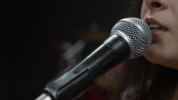 Woman singer is emotionally singing song into microphone, close up.