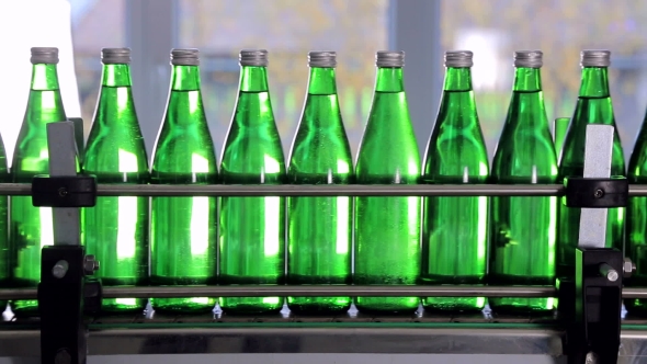 Green Bottles for Mineral Water Are Moving Along the Automatic Production Line