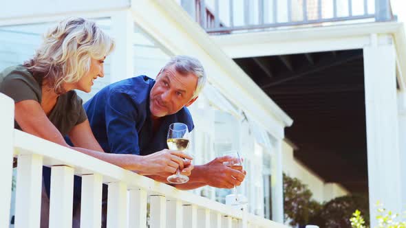 Mature couple interacting with each other while having wine in balcony