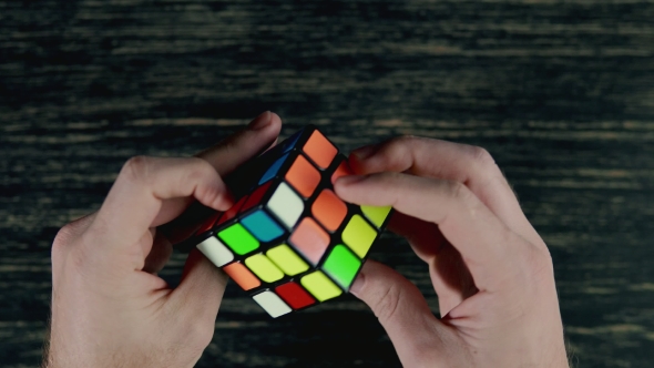 Boys Hands Solving Puzzle Cube at Dark Background. Top View