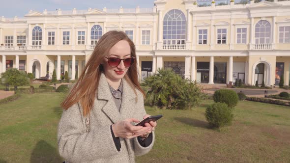 Woman Texting Message on Smartphone Outdoor in Park.