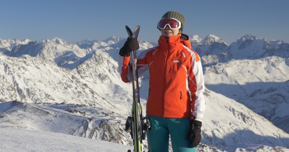 Woman Holding Skis High in Mountains