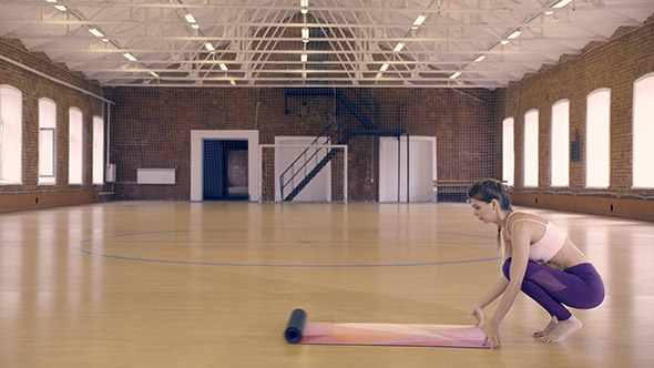 Young Woman Unfolds a Yoga Mat