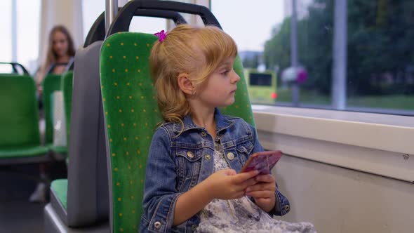 Little Girl on Smartphone Chatting Texting Browsing Social Media While Traveling By Bus in City