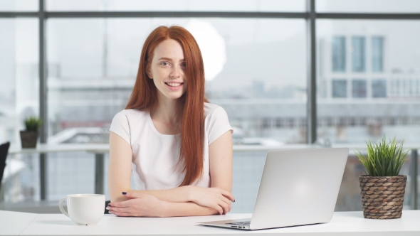Business Woman Sitting By Table with Laptop and Looking in Camera.