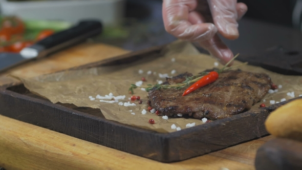 Chef Is Finishing Serving Beef Steak with Pepper and Salt