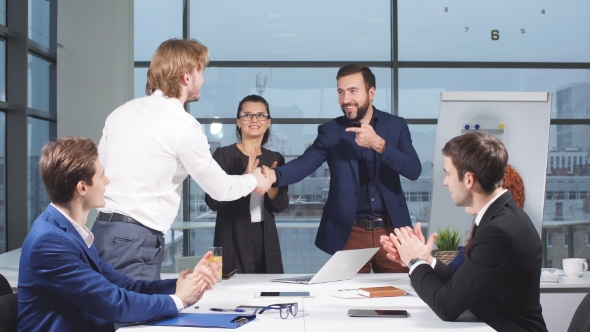 Business People Shaking Hands at Interview While Others Clap at the Office
